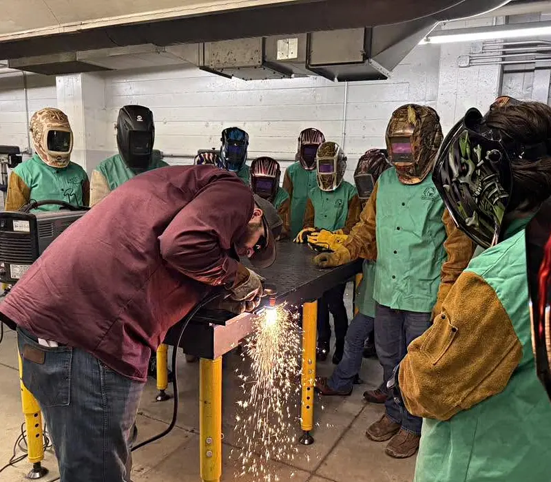 young students taking a tour and observing welding