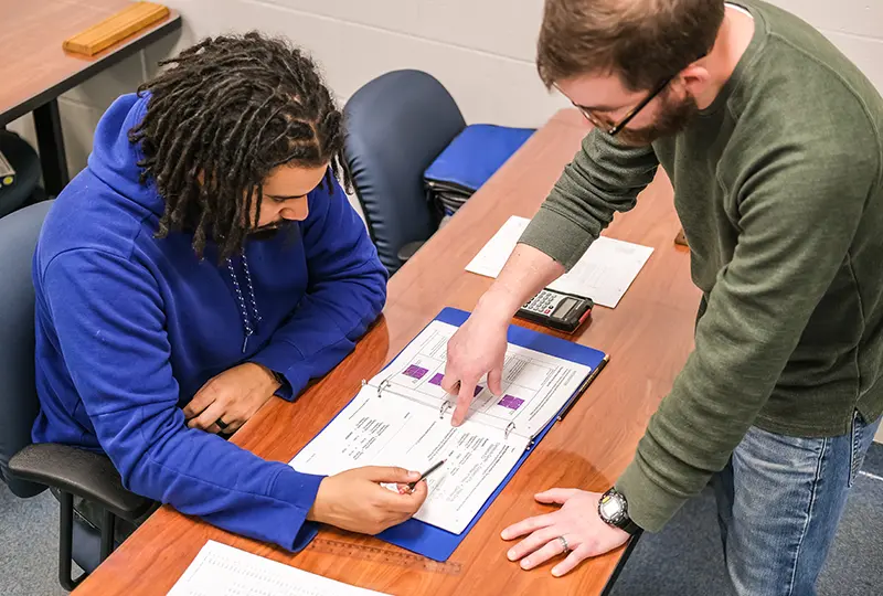 A teacher and student looking at a workbook